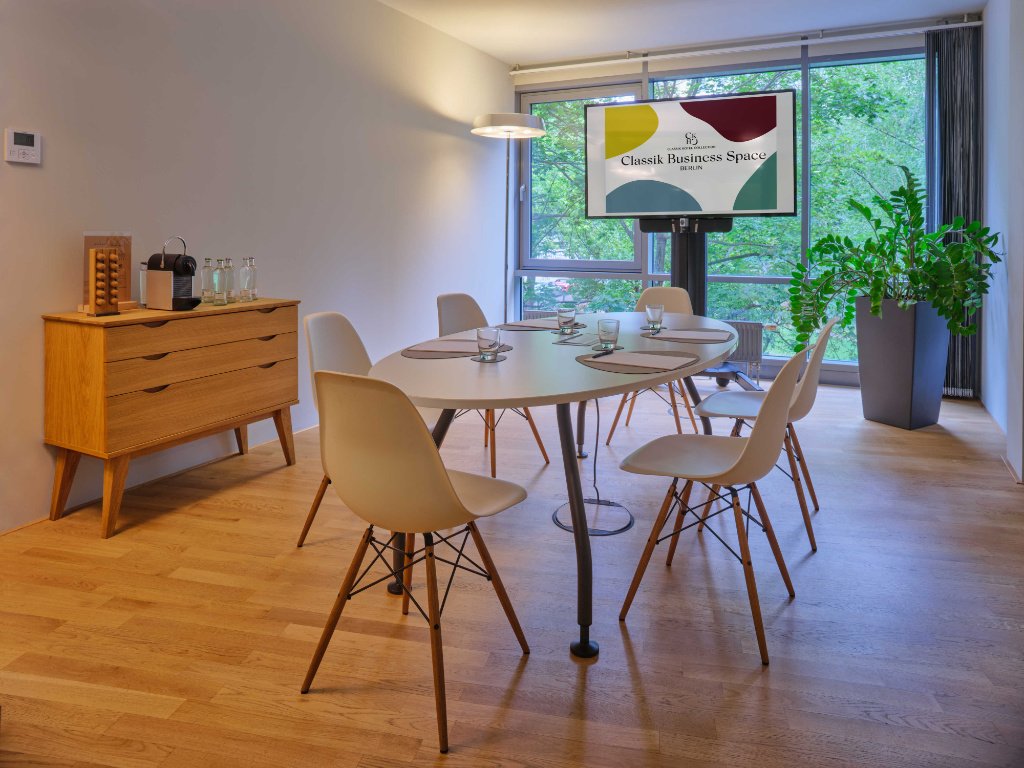 kleiner-meetingraum-mit-weissem-tisch-und-weissen-stuehlen