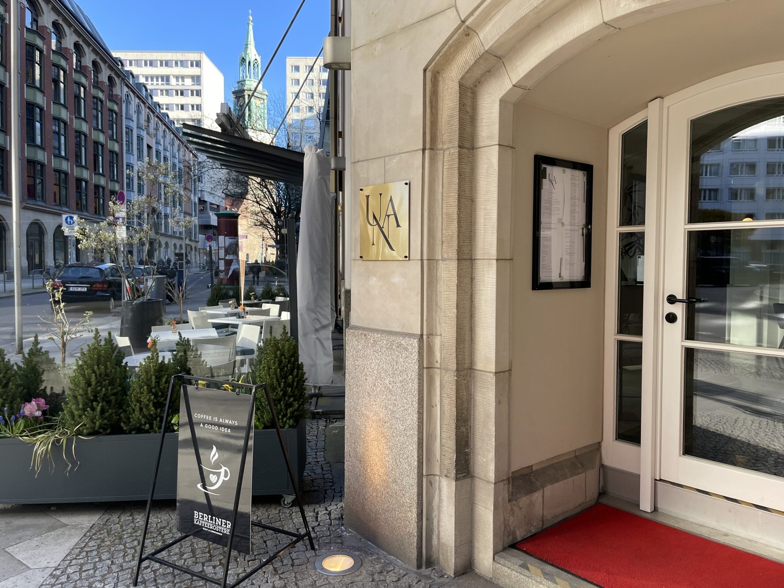 Eingang Una Berlin-Mitte, cremefarbener Steinbogen mit roten Fußbtreter,Terasse